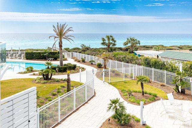 exterior space featuring a water view, a patio area, fence, and a pool