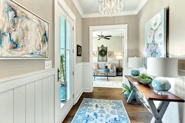 entryway with a notable chandelier, a wainscoted wall, dark wood-style flooring, and ornamental molding