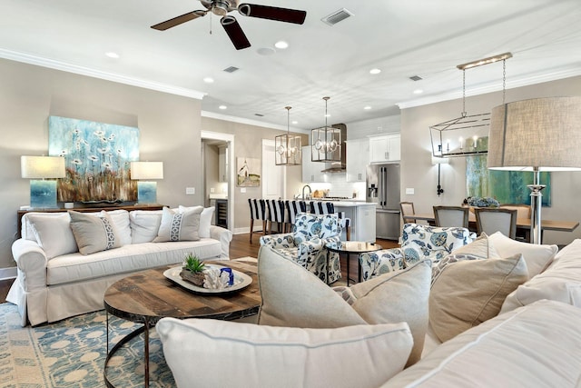 living area with crown molding, wood finished floors, visible vents, and baseboards