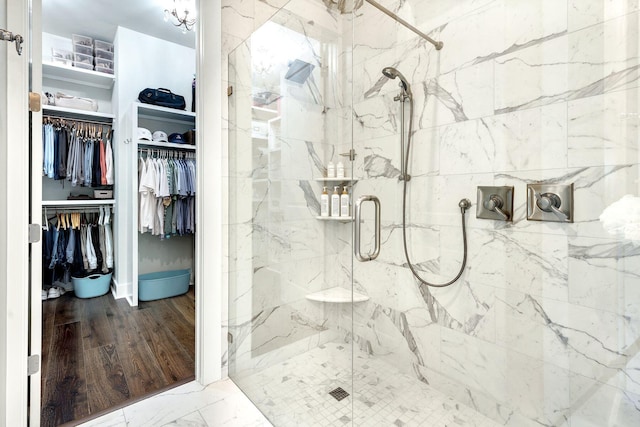 bathroom featuring a marble finish shower, marble finish floor, and a spacious closet