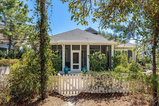 view of front of house with a sunroom, a fenced front yard, and a shingled roof