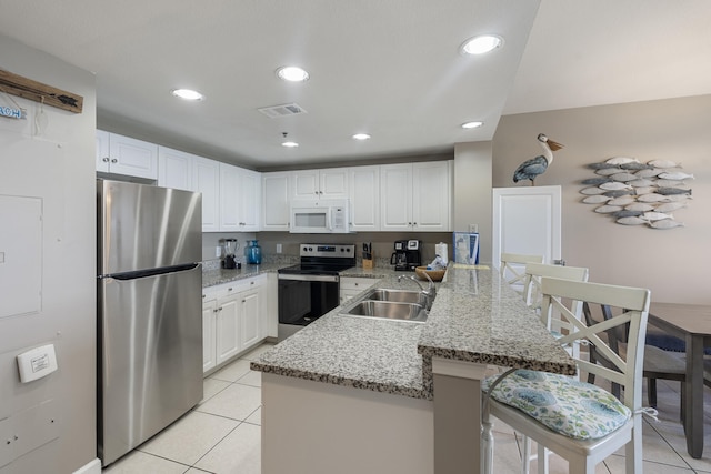 kitchen featuring a kitchen breakfast bar, a peninsula, stainless steel appliances, white cabinetry, and light tile patterned flooring