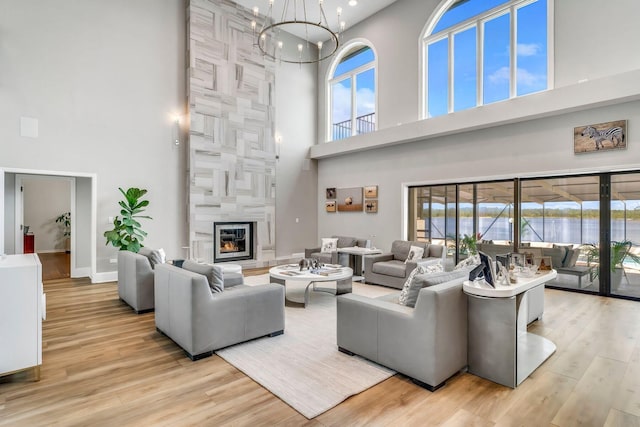 living room featuring a high end fireplace, plenty of natural light, an inviting chandelier, and wood finished floors