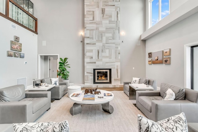 living area with a fireplace, a towering ceiling, and visible vents