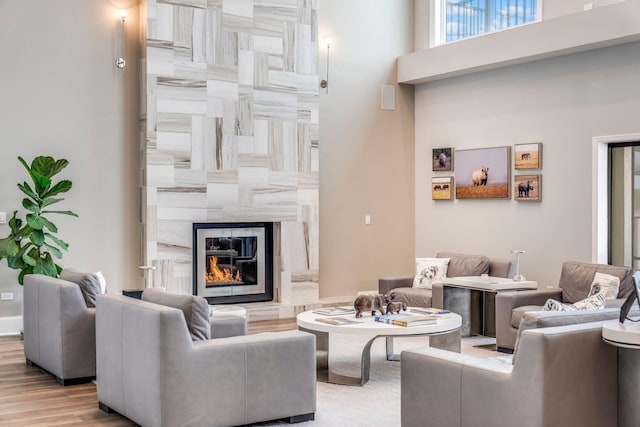 living area featuring a fireplace, wood finished floors, and a towering ceiling