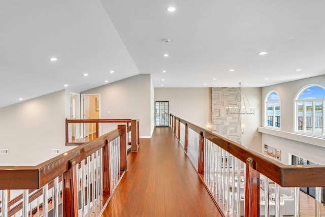 corridor with lofted ceiling, visible vents, wood finished floors, and recessed lighting