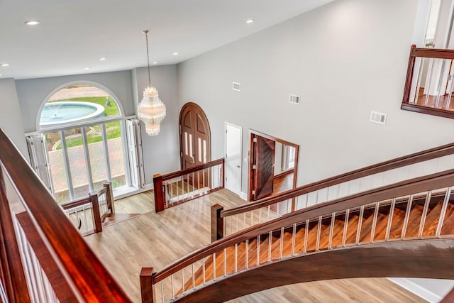 staircase featuring high vaulted ceiling, wood finished floors, visible vents, and recessed lighting