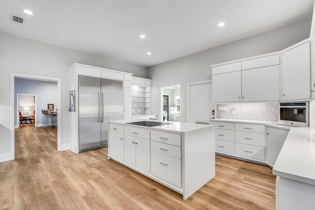 kitchen with a kitchen island, visible vents, stainless steel appliances, and light countertops