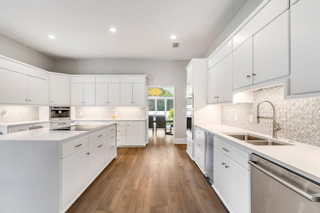 kitchen featuring black electric stovetop, wood finished floors, a sink, light countertops, and stainless steel dishwasher