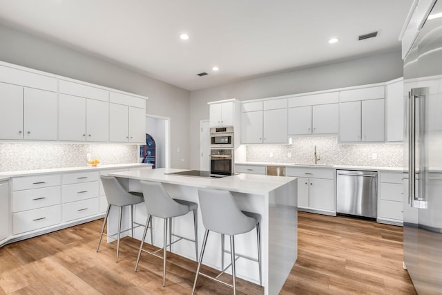 kitchen featuring light wood finished floors, visible vents, appliances with stainless steel finishes, a kitchen breakfast bar, and a center island