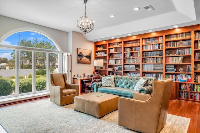 sitting room with visible vents, plenty of natural light, an inviting chandelier, and wood finished floors