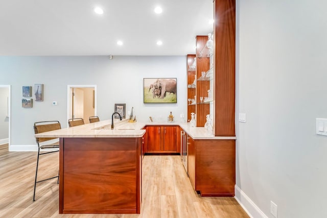 bar with light wood-type flooring, a sink, baseboards, and recessed lighting