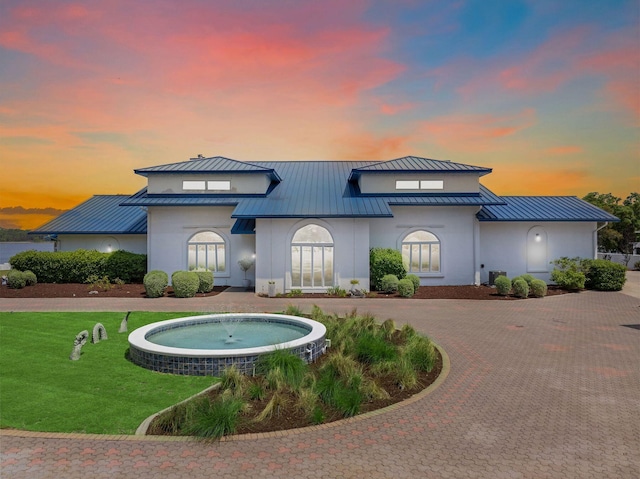 back of property featuring metal roof, a standing seam roof, and a lawn