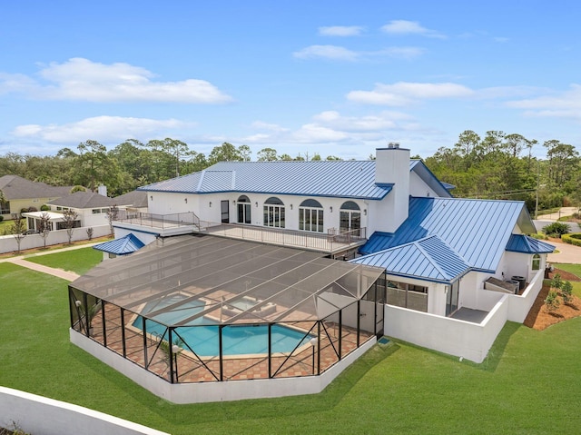 back of house with metal roof, a lanai, a fenced in pool, a standing seam roof, and a chimney