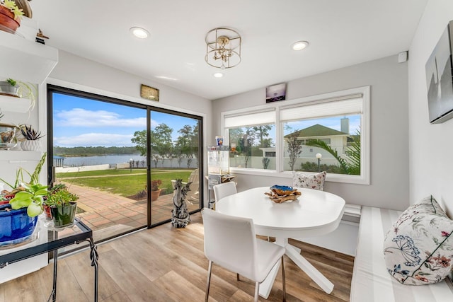 dining space featuring recessed lighting, a water view, and light wood finished floors