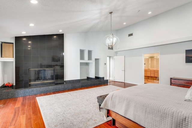 bedroom with visible vents, a tile fireplace, wood finished floors, a chandelier, and recessed lighting