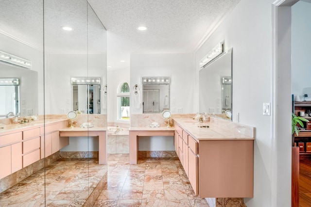 bathroom with ornamental molding, two vanities, a textured ceiling, a sink, and recessed lighting