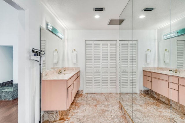 full bath with a closet, two vanities, a sink, and visible vents