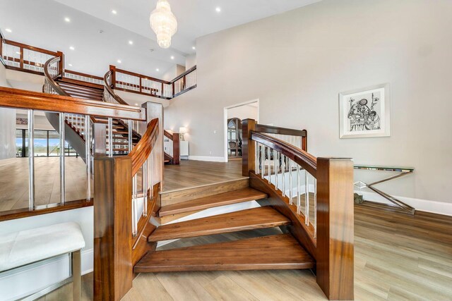 staircase featuring recessed lighting, baseboards, a high ceiling, and wood finished floors