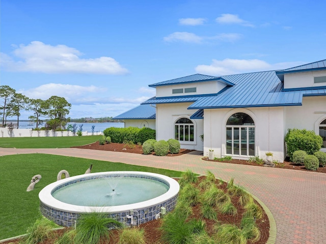 back of property featuring a standing seam roof, metal roof, and a lawn