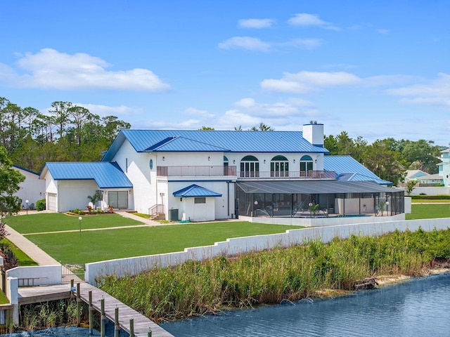 back of house with a lawn, a chimney, metal roof, a water view, and a standing seam roof