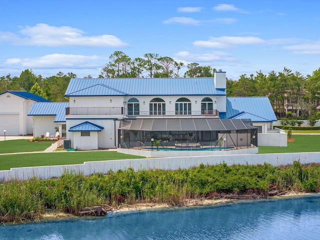 rear view of property featuring metal roof, a standing seam roof, and a balcony