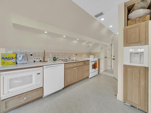 kitchen with light countertops, light tile patterned flooring, vaulted ceiling, a sink, and white appliances