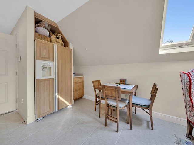 dining room with light tile patterned floors, baseboards, and vaulted ceiling