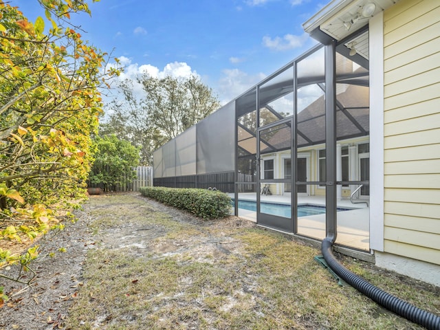 view of yard featuring glass enclosure, fence, and an outdoor pool