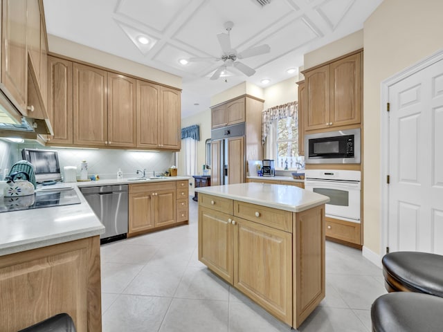 kitchen featuring light tile patterned floors, decorative backsplash, a center island, light countertops, and black appliances