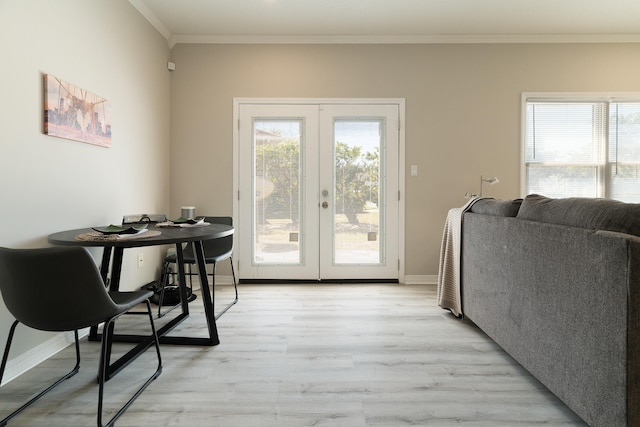 dining room with crown molding, a healthy amount of sunlight, light wood-style floors, and french doors