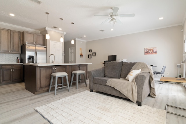 living room featuring recessed lighting, light wood-type flooring, a ceiling fan, and crown molding