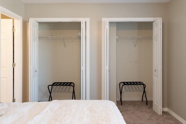 bedroom featuring baseboards, multiple closets, and carpet flooring