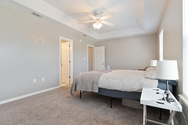 carpeted bedroom with visible vents, ceiling fan, a raised ceiling, and baseboards