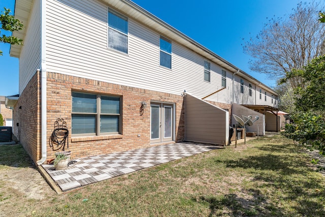 rear view of property featuring a patio, a yard, brick siding, and central AC