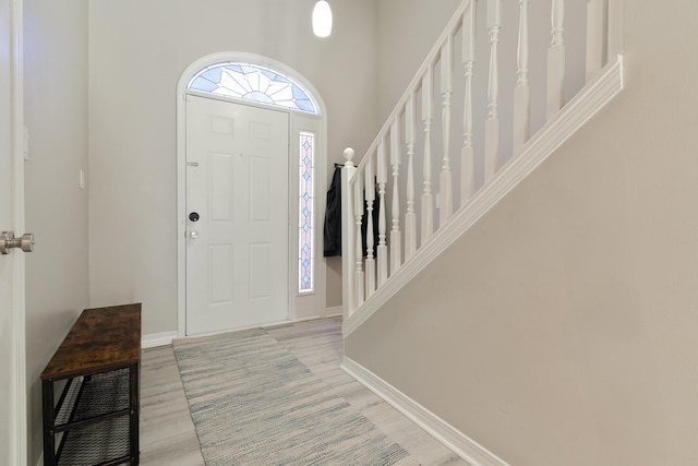 entrance foyer with light wood finished floors, stairway, and baseboards