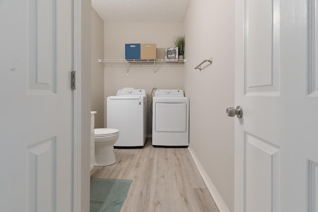 laundry room featuring washing machine and clothes dryer, baseboards, laundry area, light wood-style floors, and a textured ceiling