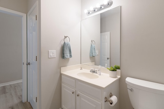 bathroom featuring toilet, wood finished floors, and vanity