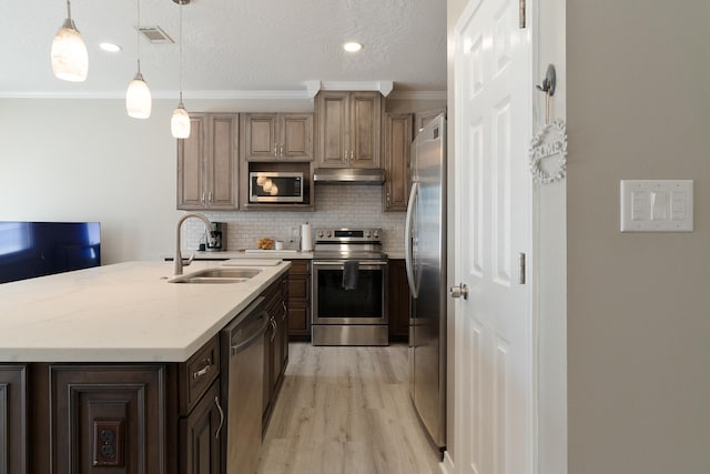 kitchen featuring a sink, decorative backsplash, stainless steel appliances, under cabinet range hood, and crown molding