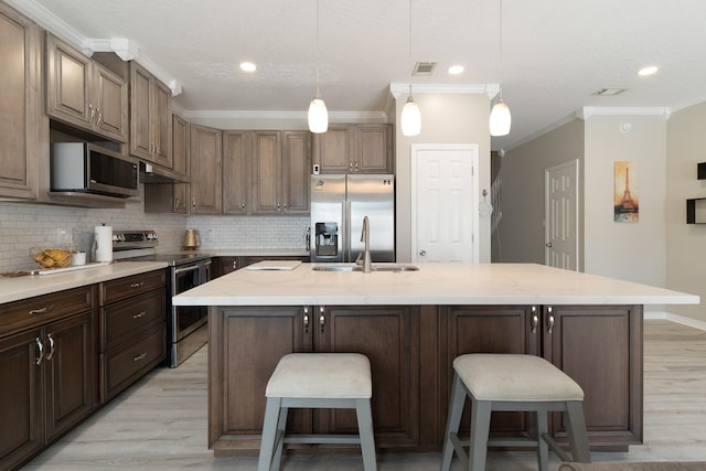 kitchen featuring visible vents, backsplash, appliances with stainless steel finishes, and a kitchen island with sink