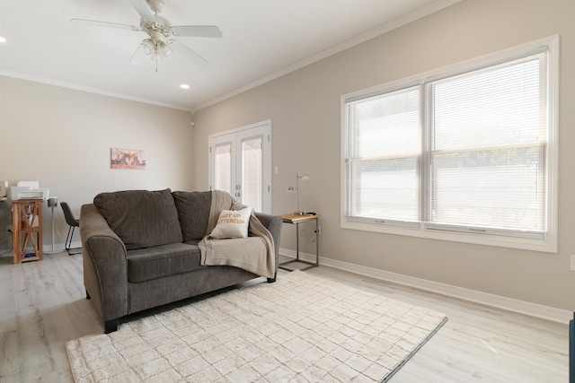 living area with baseboards, ceiling fan, crown molding, and light wood finished floors