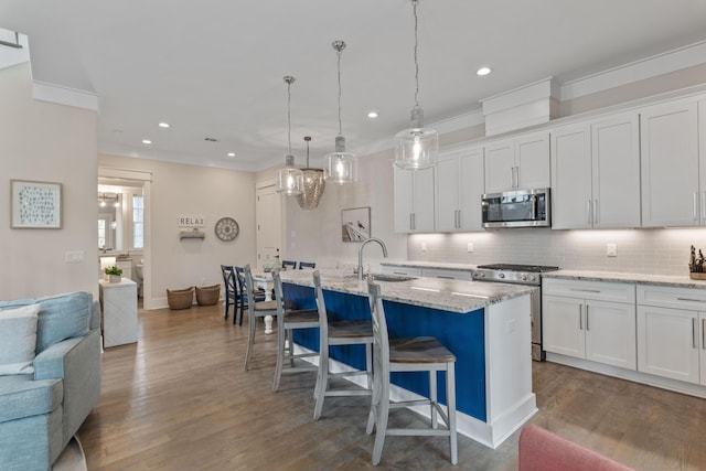 kitchen with stainless steel appliances, white cabinets, a sink, and backsplash