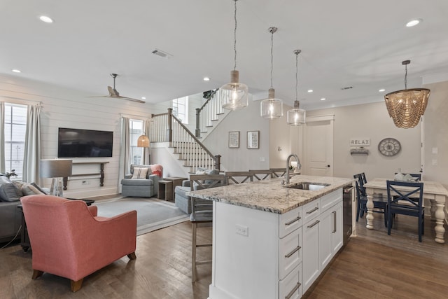 kitchen with dark wood finished floors, visible vents, open floor plan, a sink, and a kitchen bar