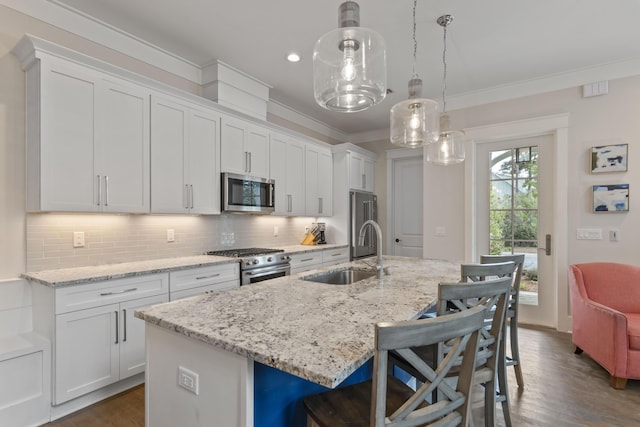 kitchen featuring a sink, a kitchen breakfast bar, white cabinets, appliances with stainless steel finishes, and crown molding