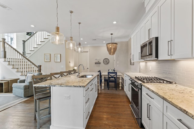 kitchen with dark wood-style floors, appliances with stainless steel finishes, a breakfast bar area, and a sink