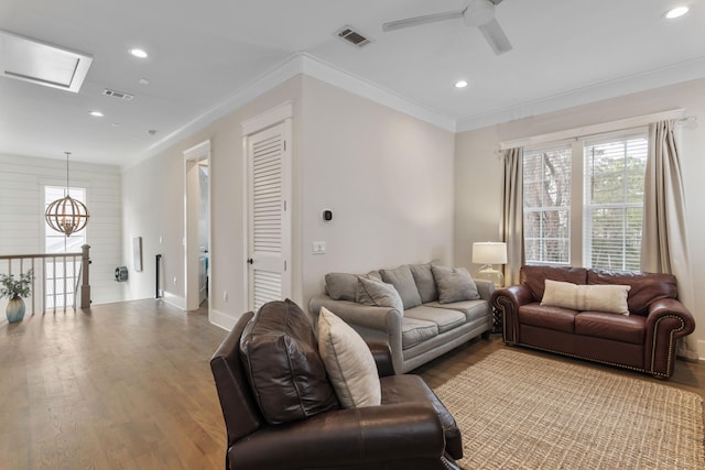 living area with recessed lighting, visible vents, wood finished floors, and ornamental molding