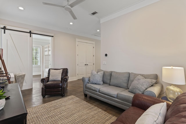 living area with a barn door, recessed lighting, dark wood-style flooring, a ceiling fan, and crown molding