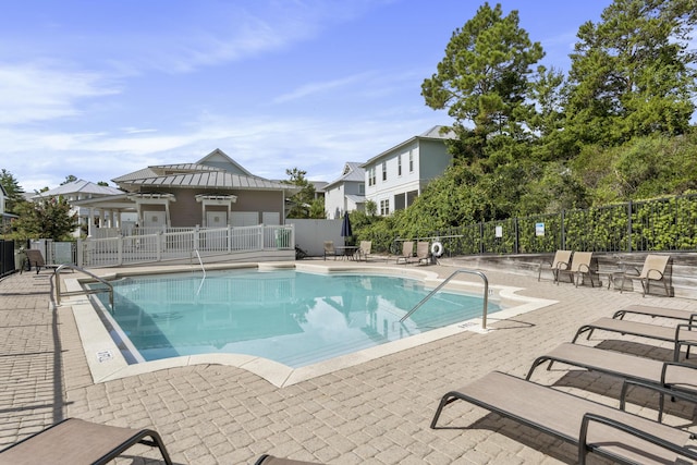 community pool with a patio and fence