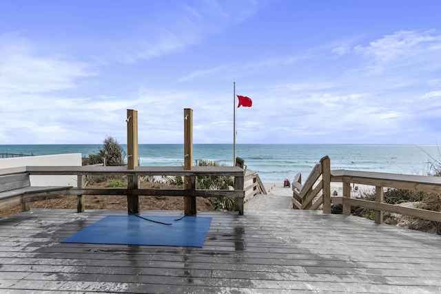 exterior space with a deck with water view and a beach view