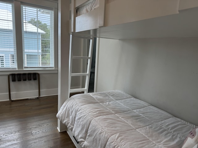 bedroom with dark wood-style floors, radiator heating unit, and baseboards